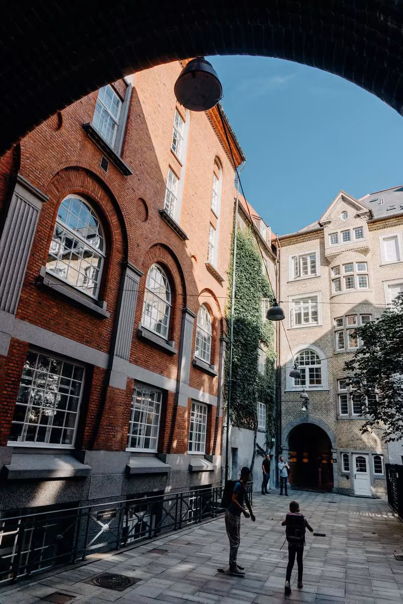 Copenhagen: Blick durch einen Bogen auf einen Innenhof mit rotem Backstein und grauem Stein.