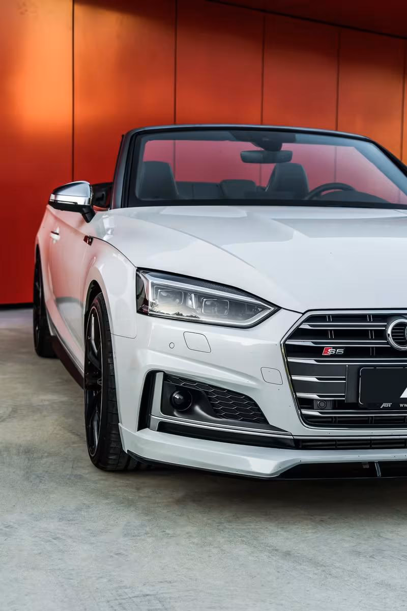 Weißer Audi S5 Cabriolet mit ABT-Modifikationen vor roter Wand