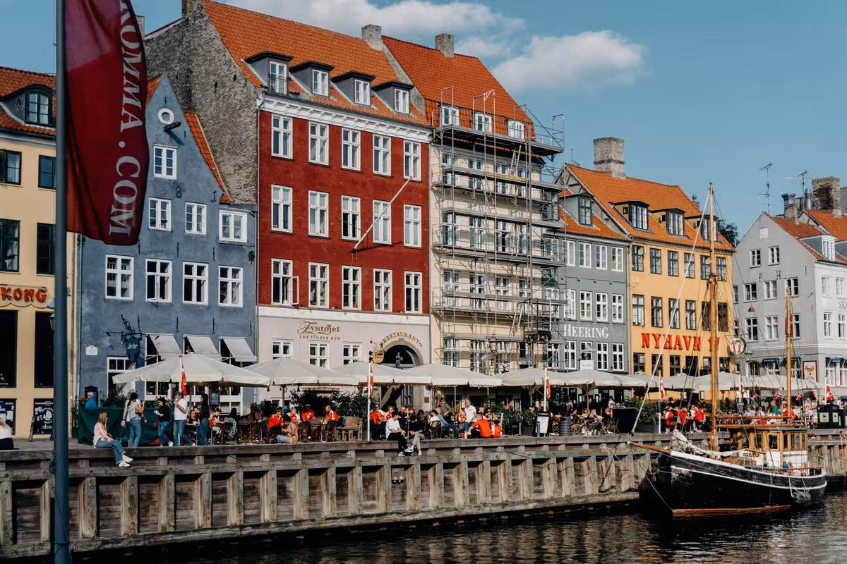 Copenhagen: Bunte Häuserfassaden am Hafen von Kopenhagen mit Boot und Menschen