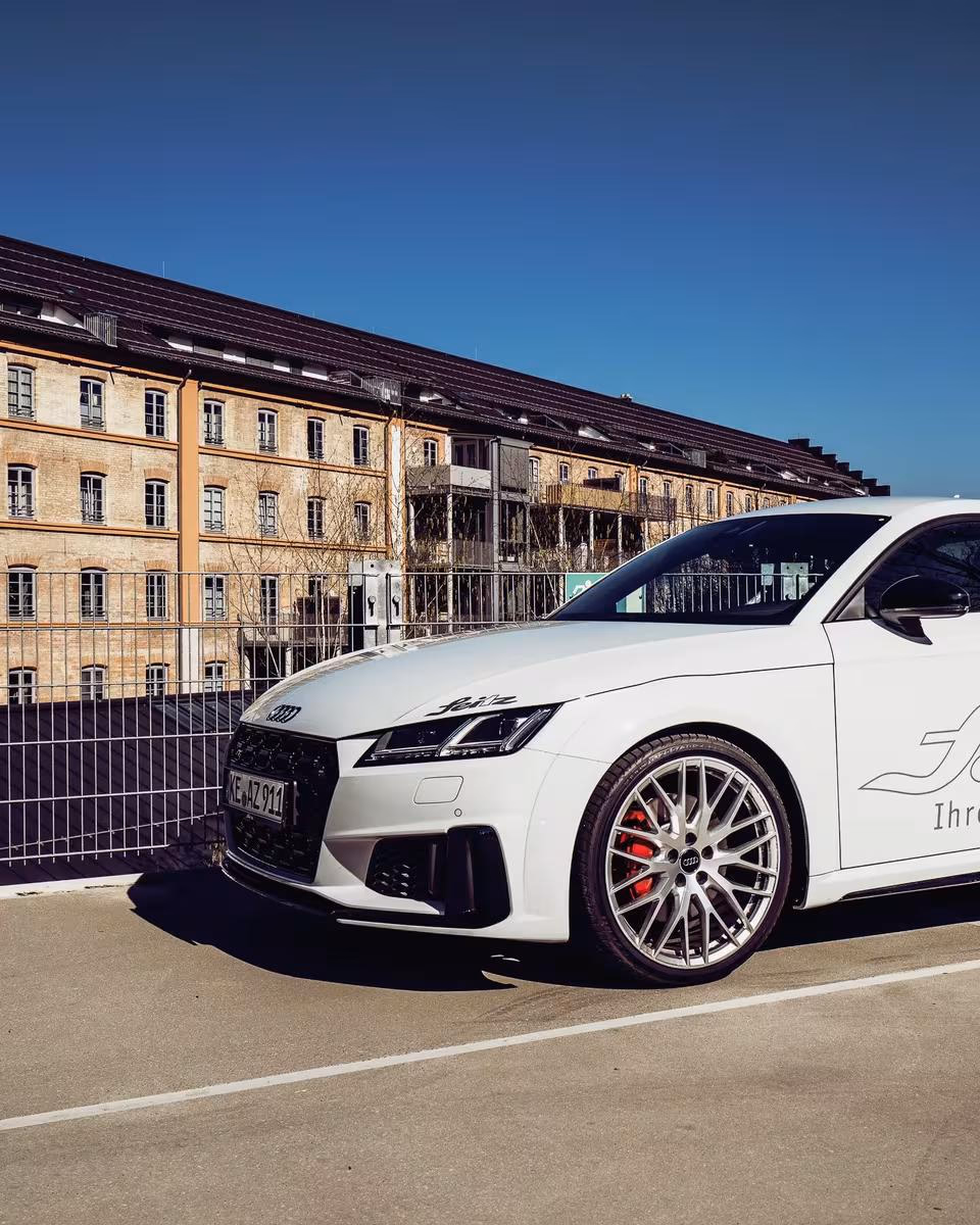 Weißer Audi S3 mit „White Widow“-Grafik vor historischer Industriehalle.