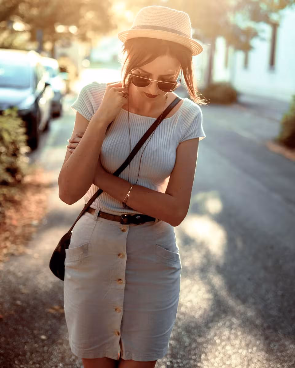 Lifestyle: Frau in weißem Outfit mit Hut und Sonnenbrille auf einer Straße.