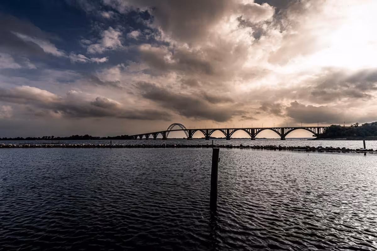 Copenhagen: Bogenbrücke über ruhiges Wasser bei dramatischem, bewölktem Himmel