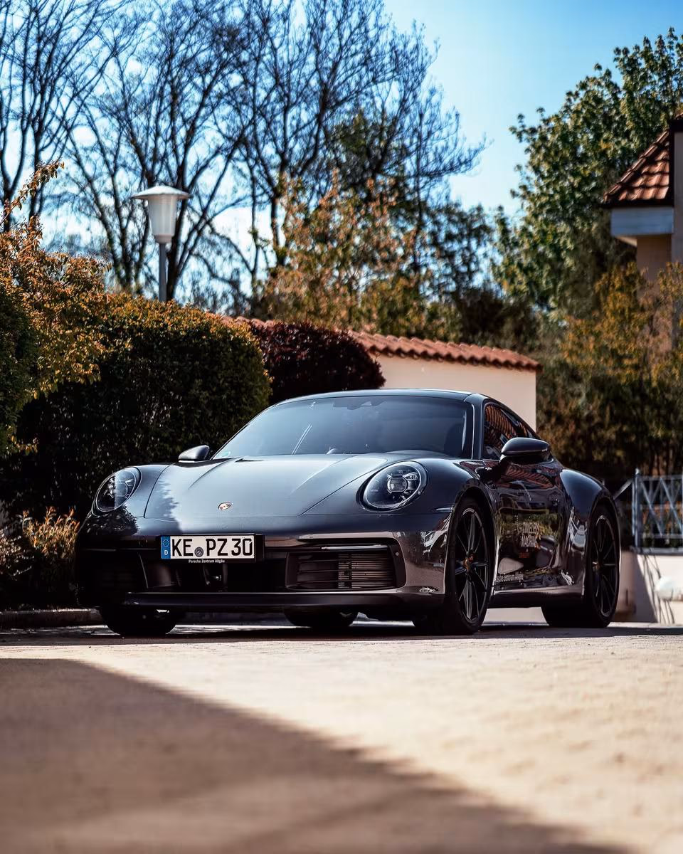 Schwarzer Porsche 911 Carrera 4S vor mediterraner Villa