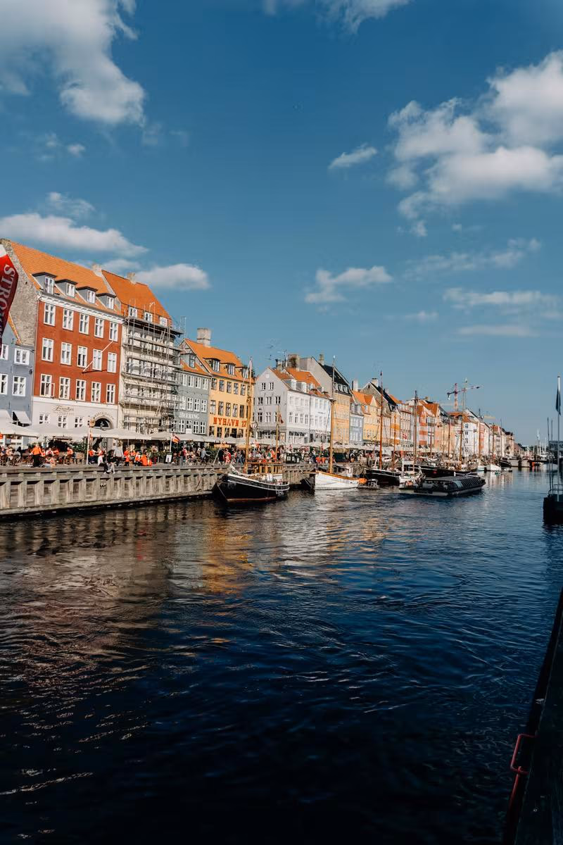 Copenhagen: Bunte Häuser und Boote am Hafen von Kopenhagen unter blauem Himmel.