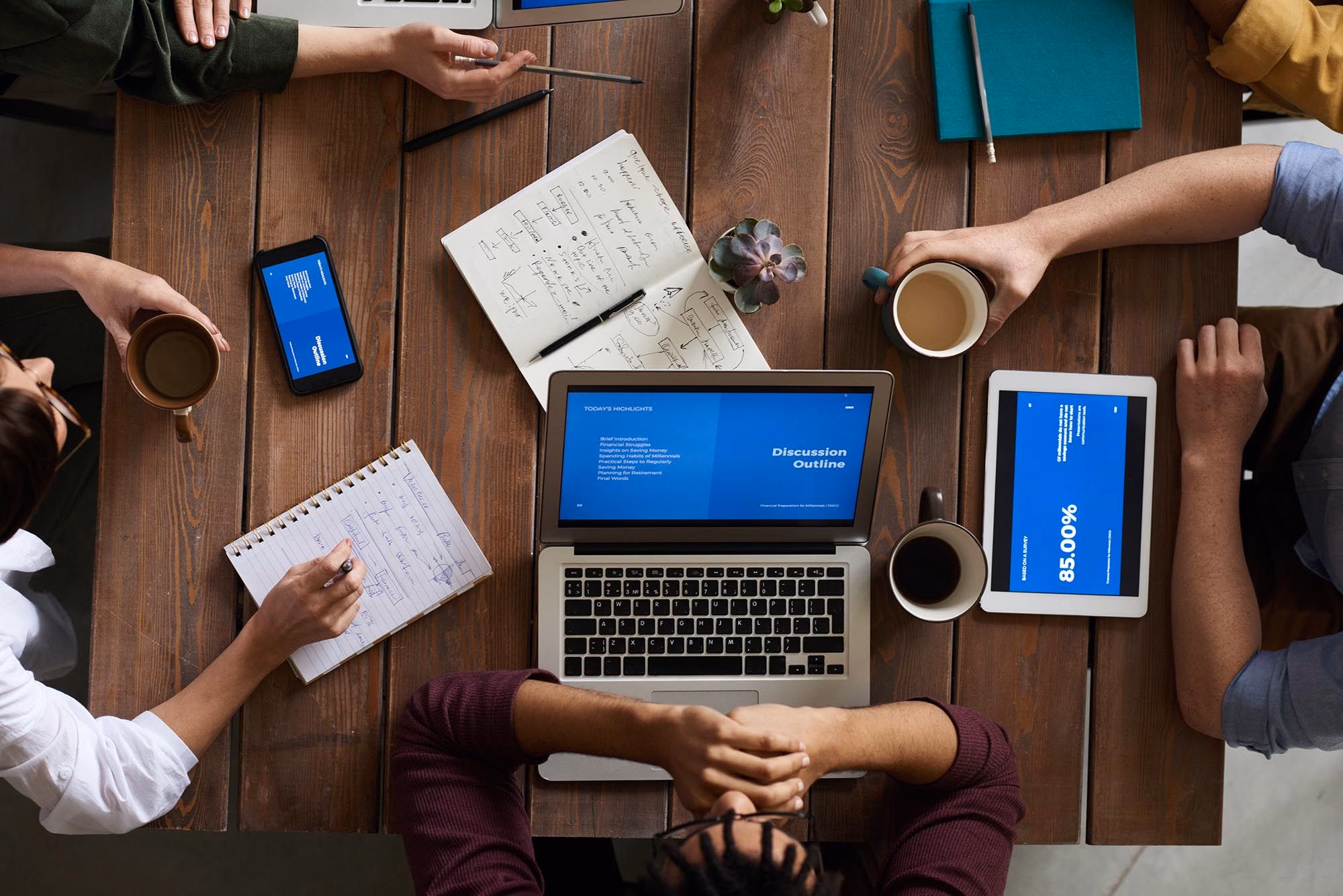 Group of people working at a table with notebooks and laptops 