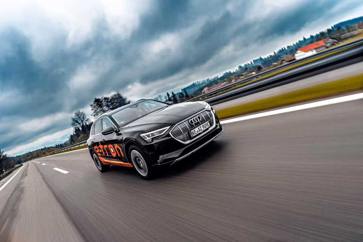 Black Audi e-tron with orange lettering driving on a highway.