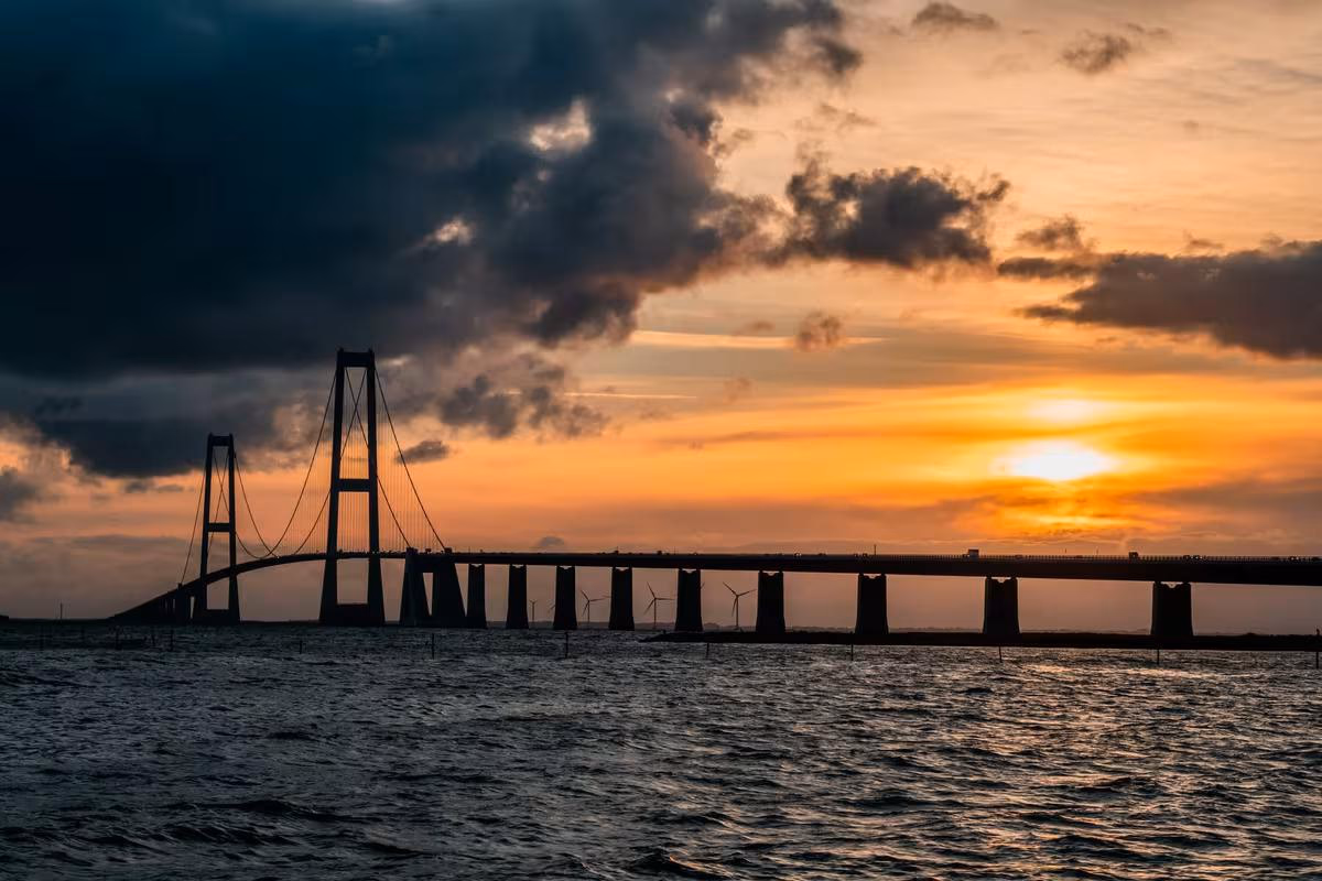 Copenhagen: Silhouette einer Hängebrücke über dem Meer bei dramatischem Sonnenuntergang.