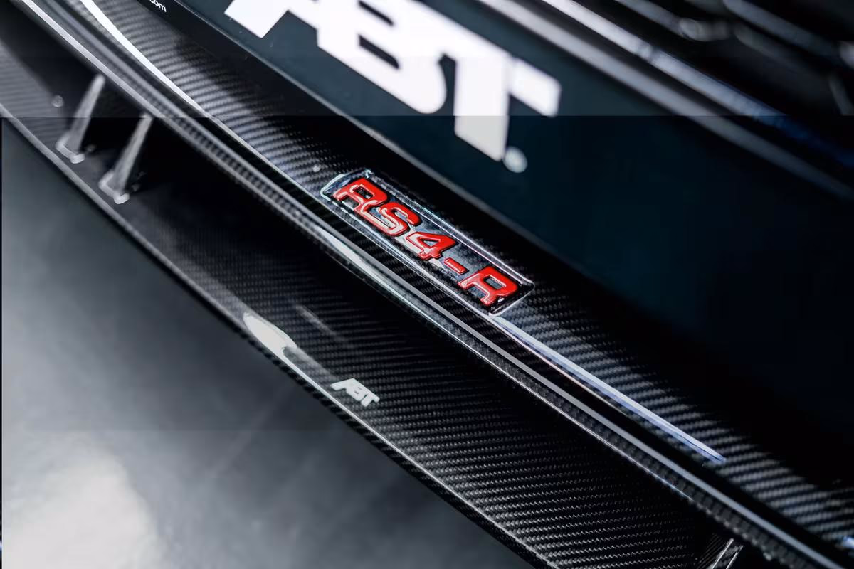 Audi: Nahaufnahme eines Carbon-Autos mit rotem RS4-R-Emblem und ABT-Logo.