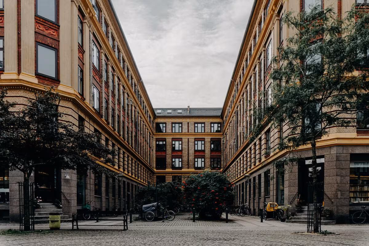 Copenhagen: Historischer Innenhof mit Backsteinfassaden, Bäumen und gepflastertem Boden