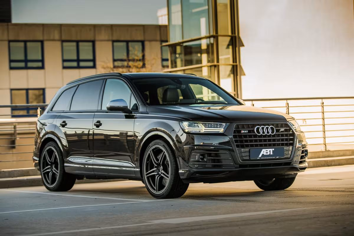 Schwarzer Audi SQ7 mit ABT-Logo vor modernem Gebäude