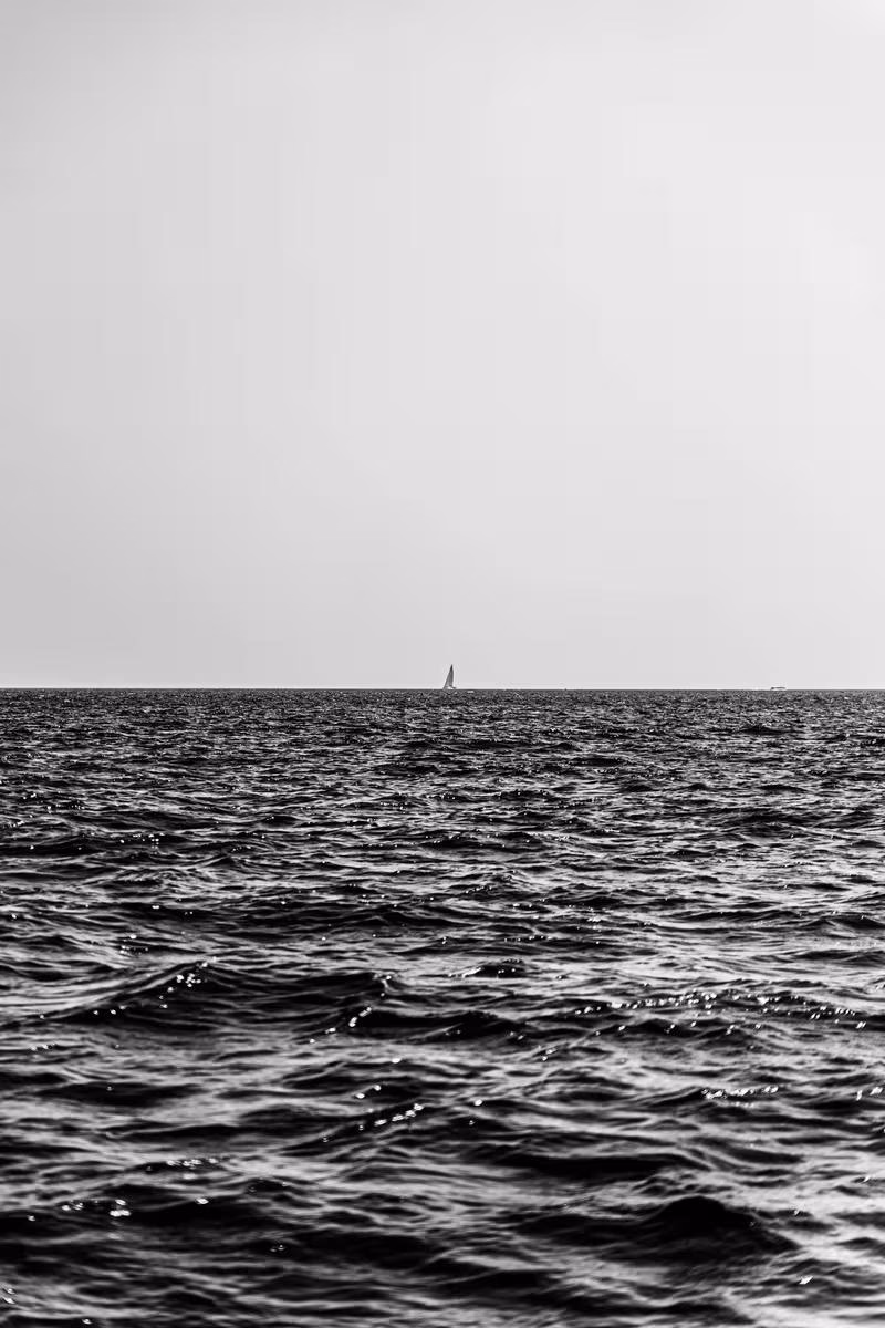 Thailand: Schwarz-Weiß-Aufnahme: Segelboot am Horizont über welliger See