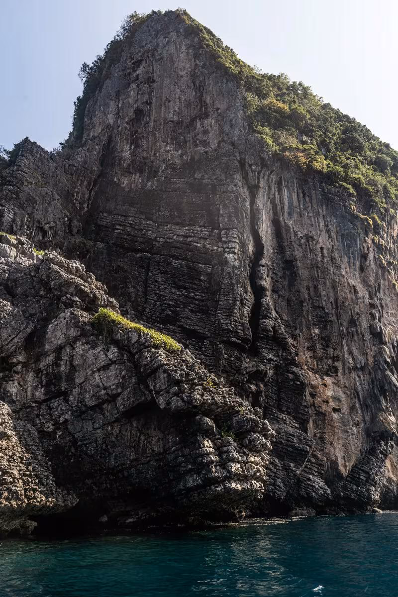 Thailand: Steile, bewachsene Klippe über türkisfarbenem Meerwasser