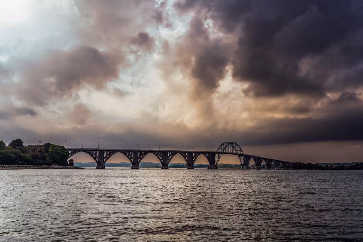 Copenhagen: Bogenbrücke über einen Fluss unter dramatischem, bewölktem Himmel.