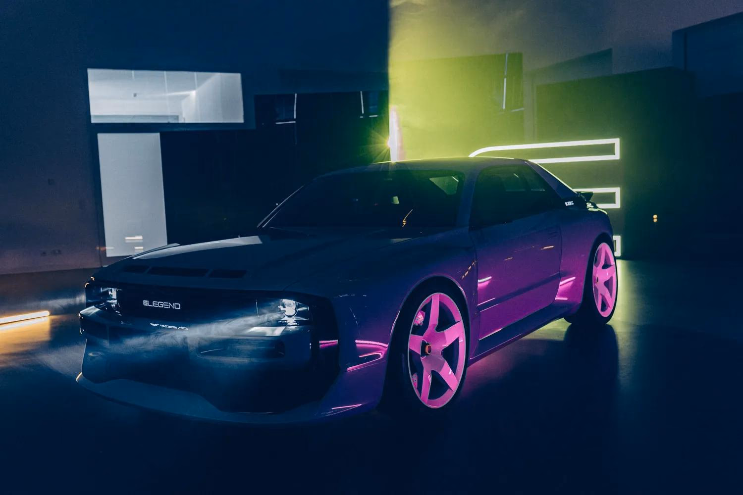 E-Legend Elektroauto mit pinken Felgen in dunkler Halle unter Neonlicht.
