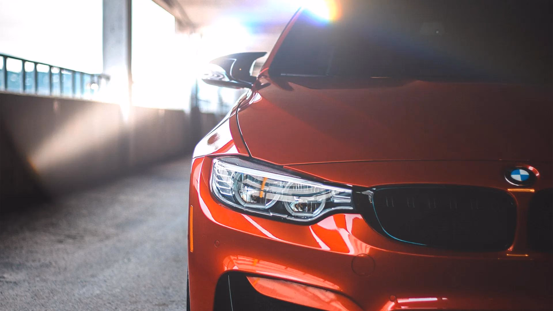 Rotes BMW mit sichtbarem Logo und Scheinwerfer in einer beleuchteten Halle.