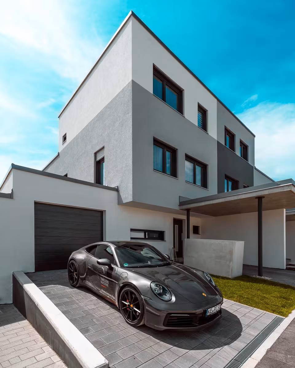 Seitz: Grauer Porsche 911 vor modernem Wohnhaus mit Garage