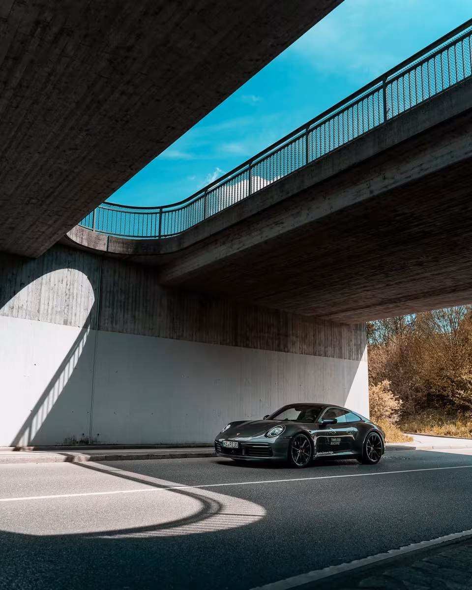 Grauer Porsche 911 Carrera 4S unter einer Betonbrücke
