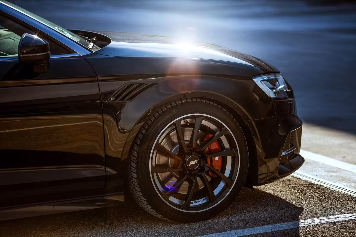 Audi: Schwarzer Sportwagen mit ABT-Felge und roter Bremse im Sonnenlicht