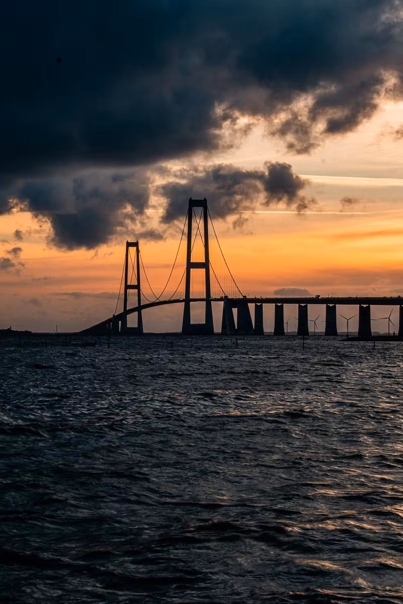 Copenhagen: Silhouette einer Hängebrücke über dem Meer bei dramatischem Sonnenuntergang.
