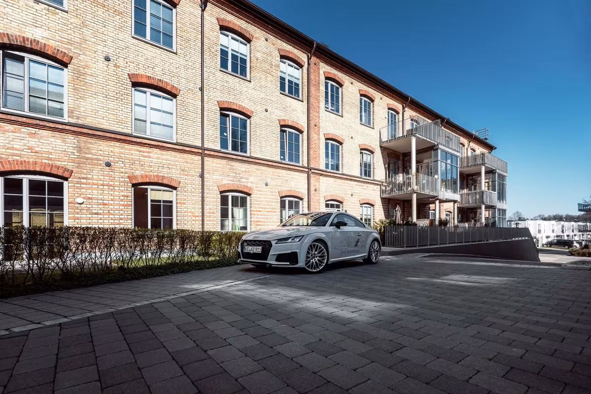 Silberner Audi RS 3 mit White-Widow-Design vor einem Ziegelgebäude