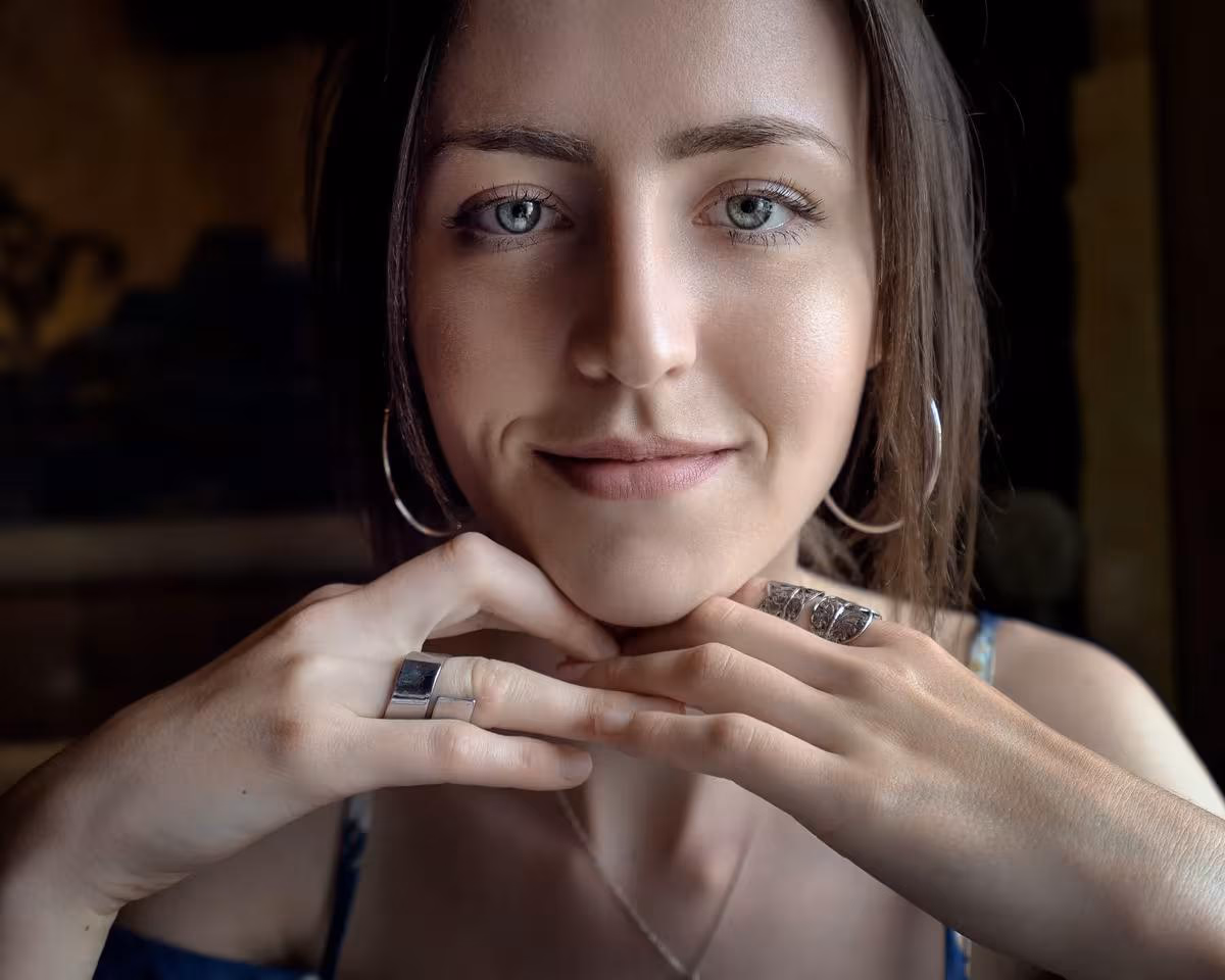 Lifestyle: Porträt einer Frau mit Ringen und Ohrringen, Hände unter dem Kinn.