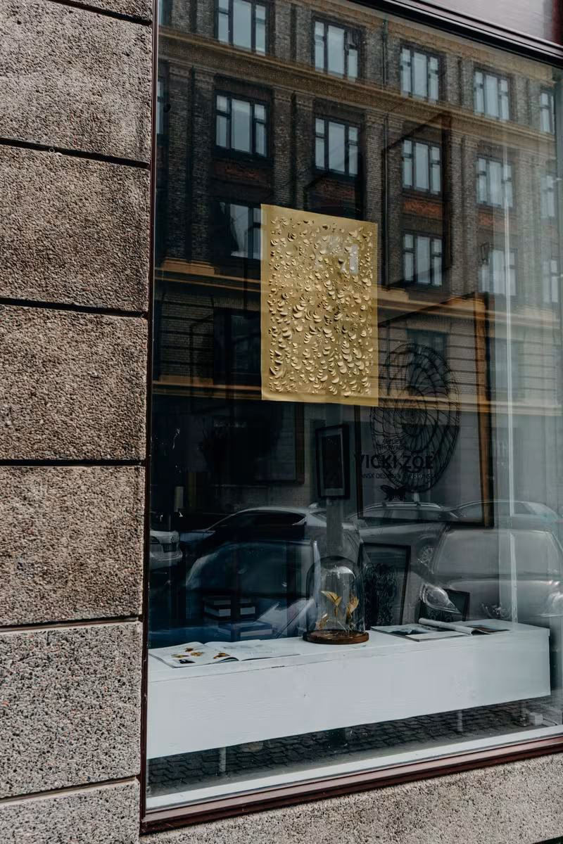 Copenhagen: Goldene Relief-Platte mit organischen Mustern in einer Galerievitrine.