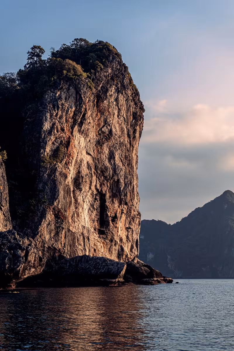 Thailand: Steile Klippe mit Vegetation am Wasser bei Sonnenuntergang