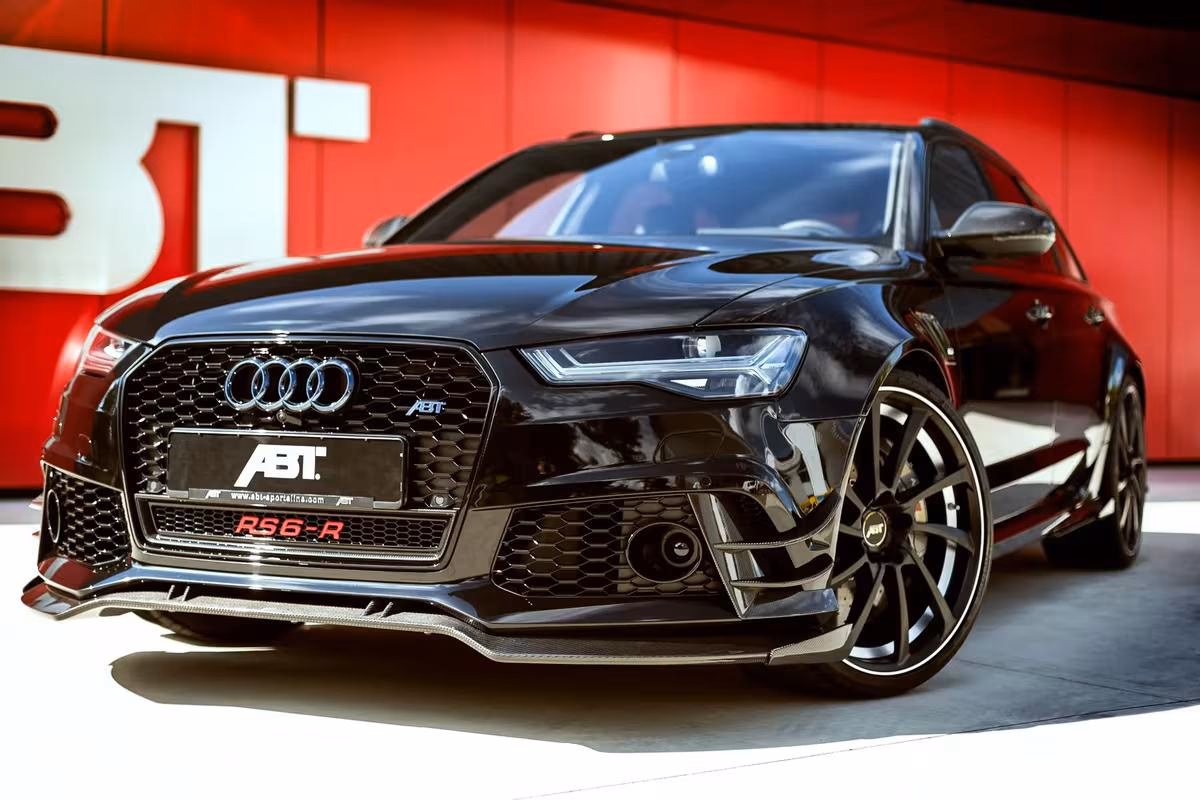 Audi: Schwarzer ABT RS6-R im Frontansicht vor roter ABT-Wand