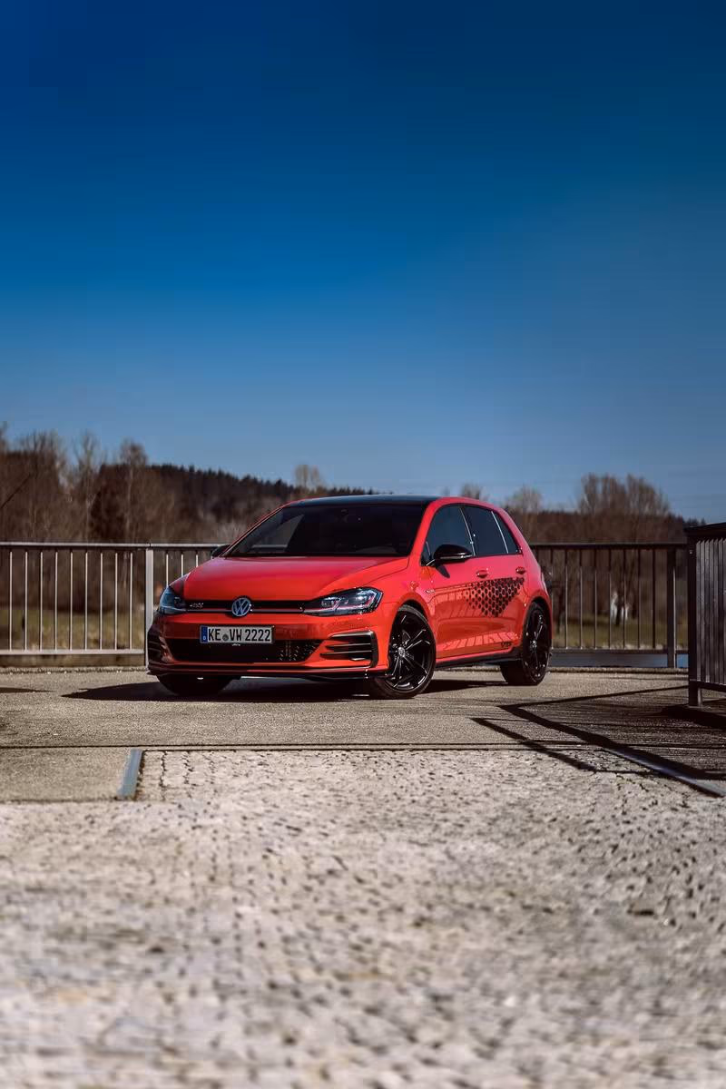 Volkswagen: Roter VW Golf GTI mit schwarzem Dach und Felgen auf einer Brücke.