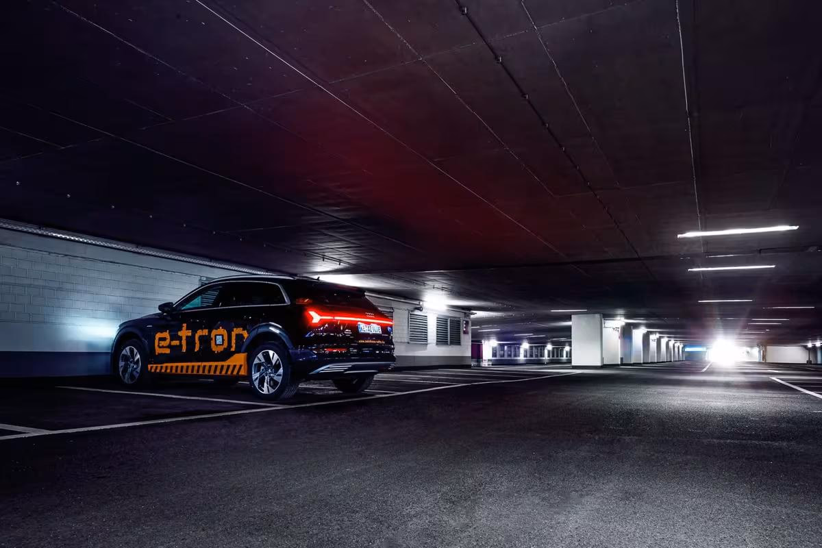Black Audi e-tron with orange wrap design in an underground parking garage.
