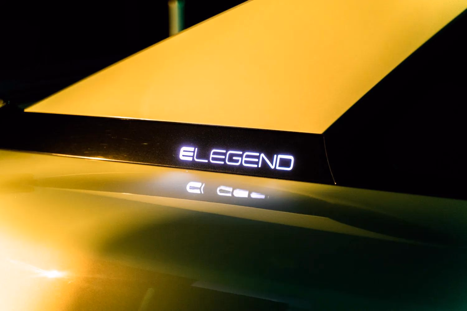Leuchtendes E-LEGEND-Logo auf dunklem Fahrzeug im gelben Licht