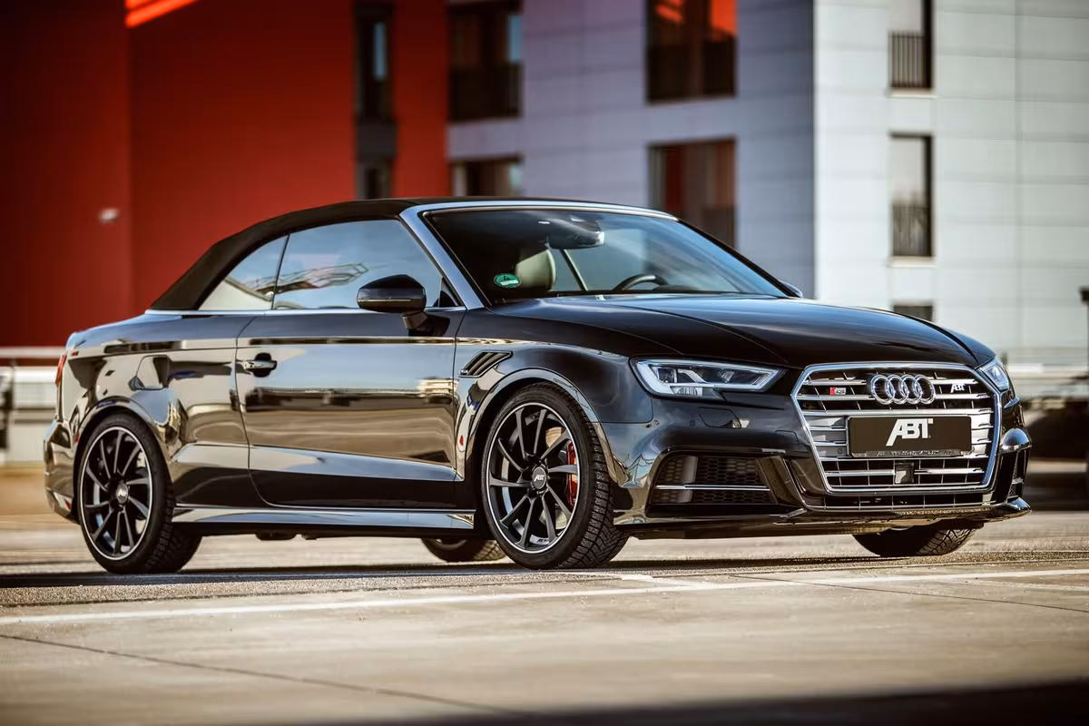 Schwarzer ABT-Audi RS5 Cabriolet vor modernem Gebäude mit roter Fassade