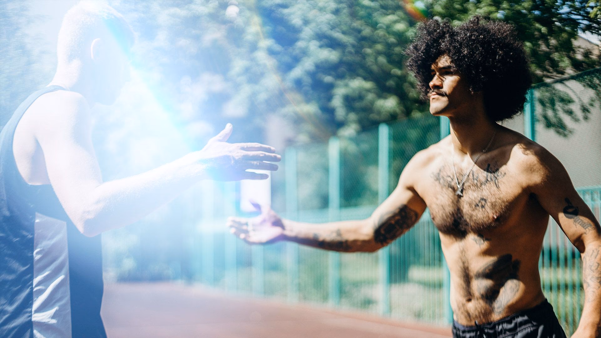Zwei Männer geben sich auf einem Sportplatz die Hand.