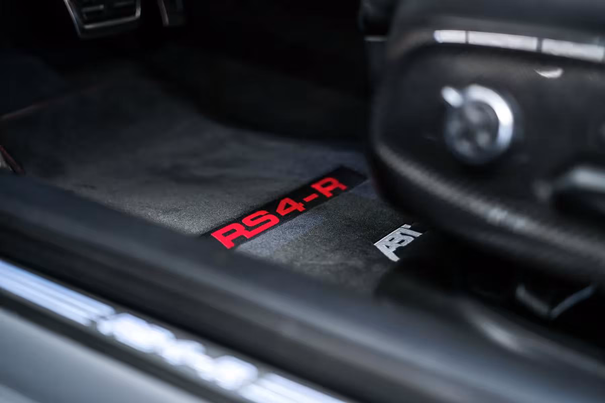 Audi: Schwarzer Autoteppich mit roter RS4-R- und weißer ABT-Bezeichnung im Fußraum.