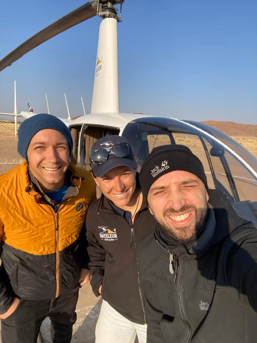 Fujifilm: Drei Personen lächeln vor einem Hubschrauber in der Wüste.