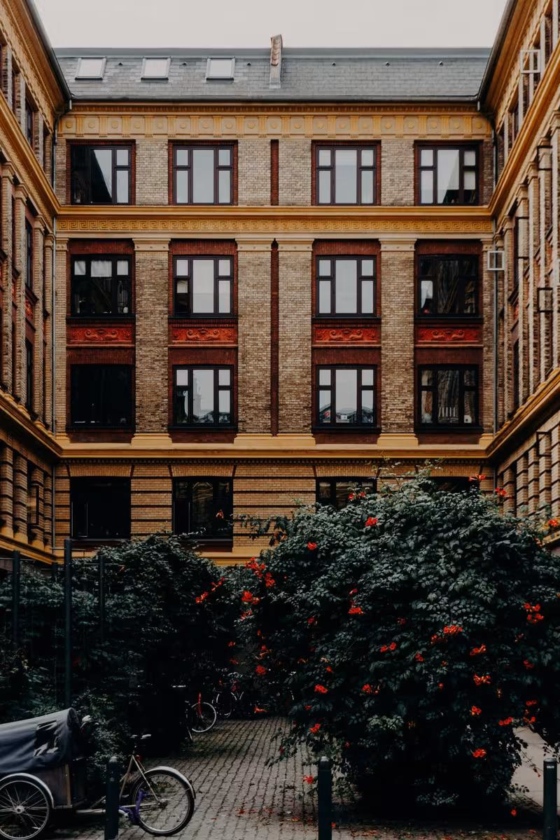 Copenhagen: Historisches Backsteinhaus mit roten Fensterrahmen und blühenden Rosen im Innenhof.