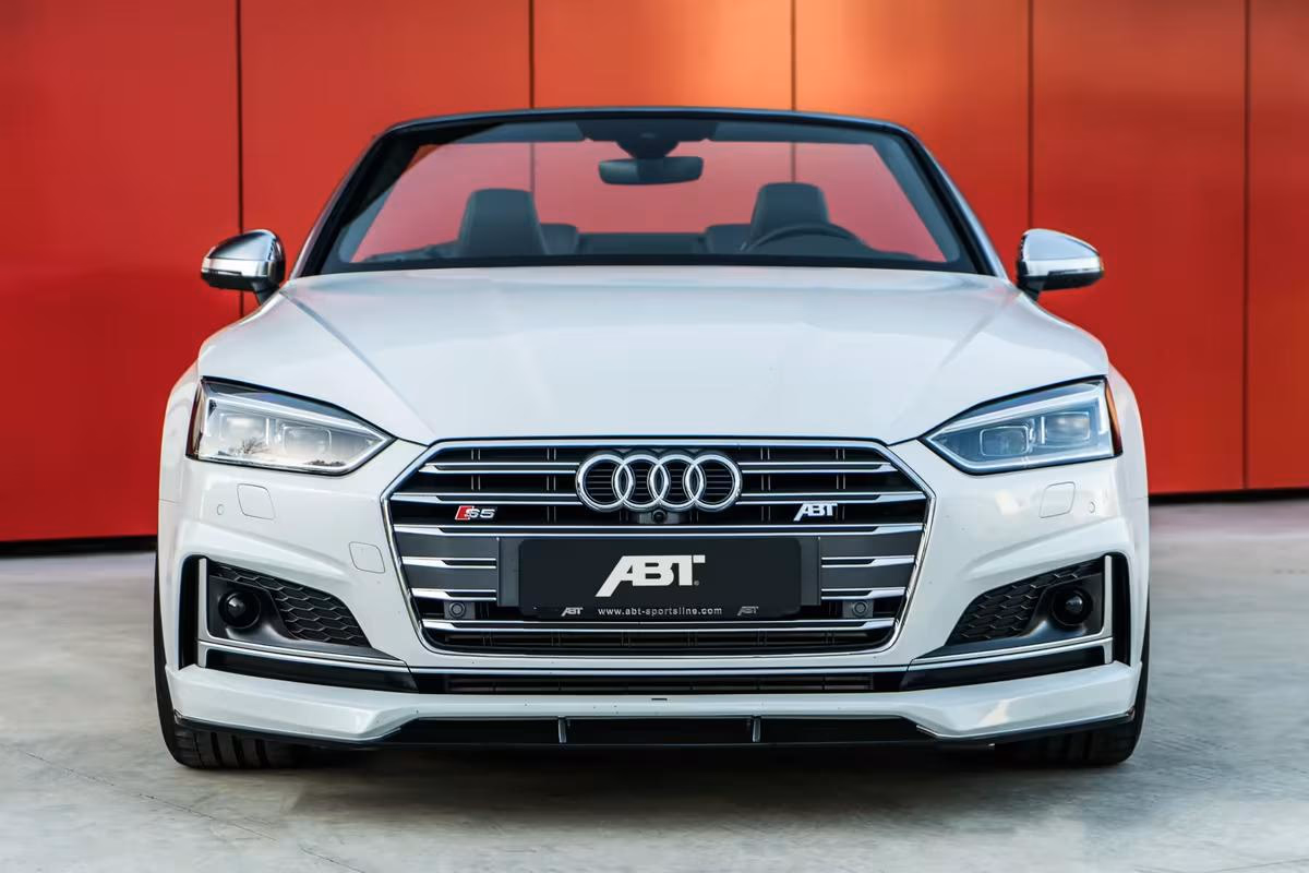 Frontansicht eines weißen ABT Audi S5 Cabriolets vor roter Wand