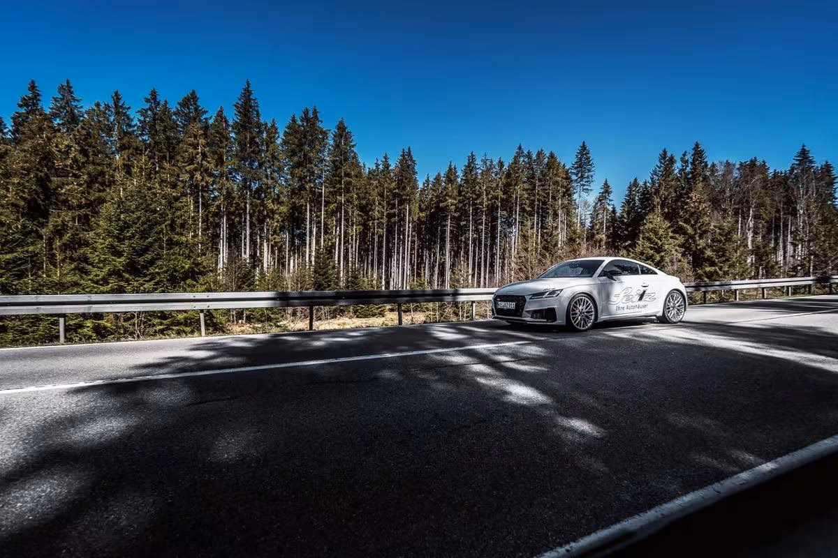 Silberner Audi mit „White Widow“-Lackierung auf Landstraße vor Nadelwald