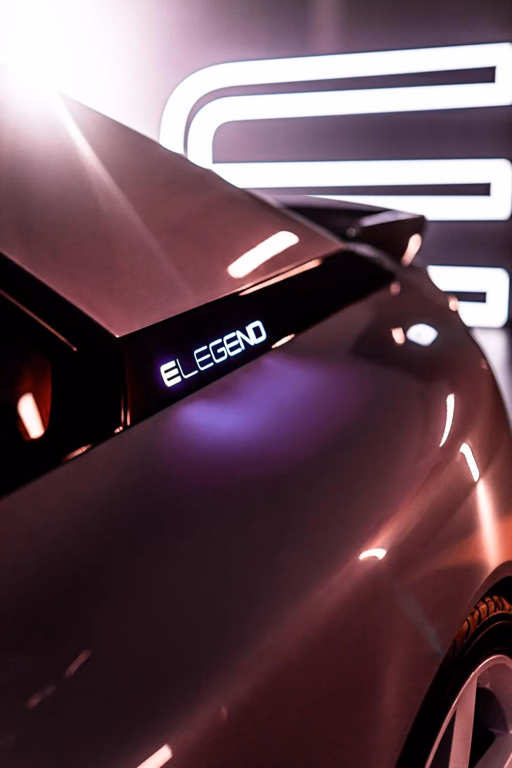Rückseite eines Autos mit leuchtendem „E-LEGEND“-Schriftzug vor dunklem Hintergrund