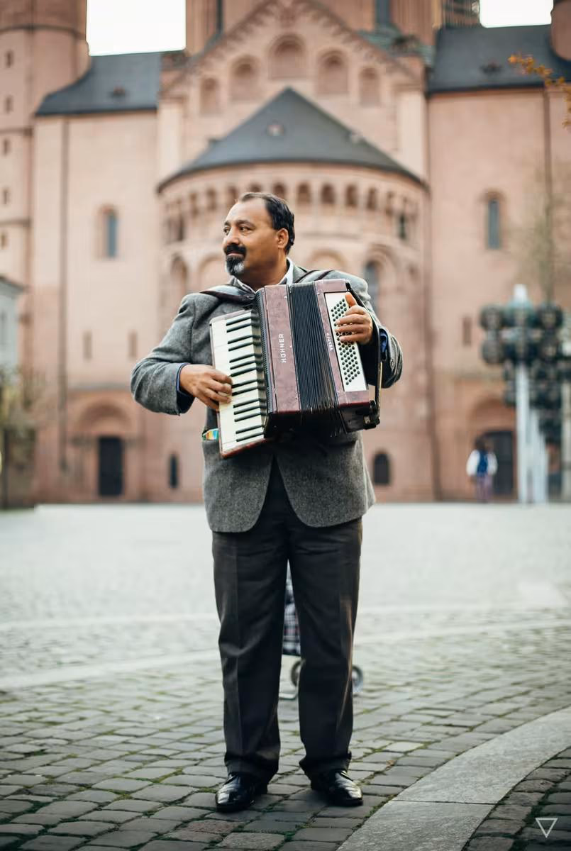 Lifestyle: Mann spielt Akkordeon auf einem Platz vor einer historischen Kirche.